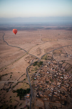 Balloon Over Desert Settlement with Winding Roads and Flat Roofs