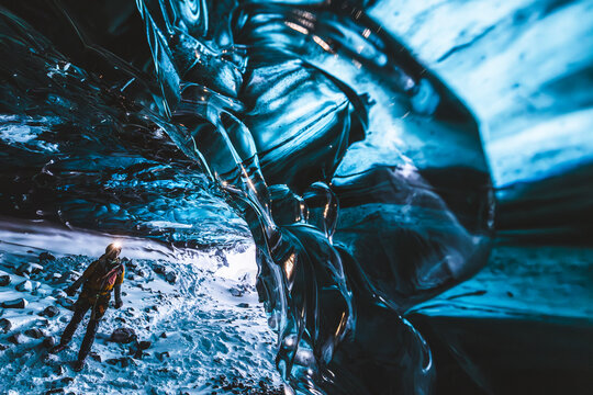 Woman with headlamp explores ice cave in Iceland