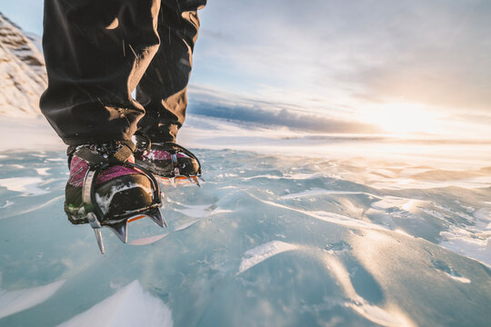 close up of crampons biting into surface of glacier ice at sunset