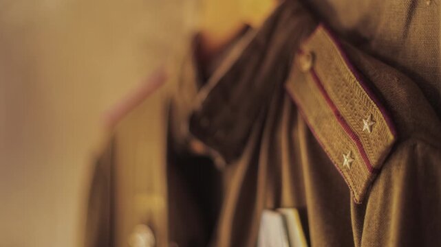Close-up view of olive green Soviet officer uniform, prominent shoulder strap denoting rank of lieutenant, attached medals of honor below, historical war symbolism on display. Reenactment props