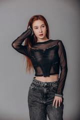 Fototapeta premium Model is a beautiful young girl in a transparent black longsleeve and jeans in the studio