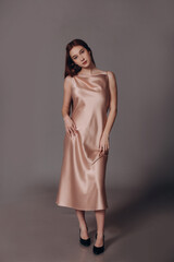 Fototapeta premium The model is a beautiful young girl in a pink silk dress in the studio