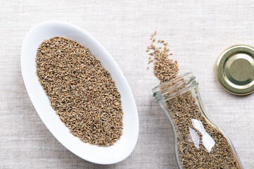 Aniseed, anise seeds, in white bowl on linen. Anise fruits, mistakenly called seeds, from the plant Pimpinella anisum, used to flavor food, candy, and alcoholic drinks, around the Mediterranean. Photo