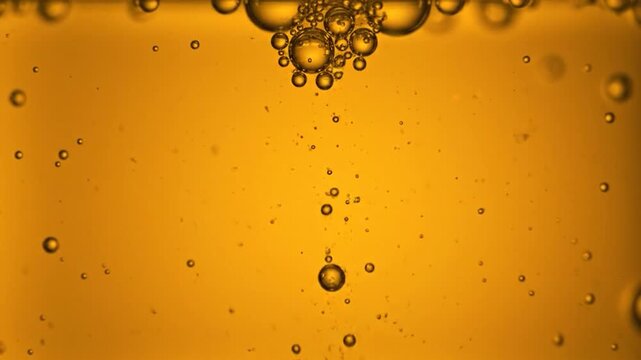 Numerous small and large bubbles suspended in a golden, viscous liquid