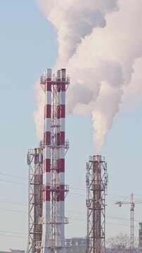 Thermal power plant pipes with vapor rising to the sky. Large vapor rising in front of the blue sunny sky.