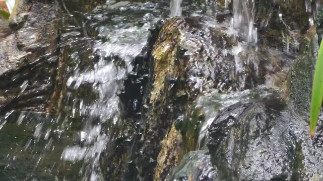 Close-up footage of clear water flowing rapidly over natural rocks in a small stream. The movement of splashing water and wet stone textures creates a calming and refreshing nature scene. Ideal for co