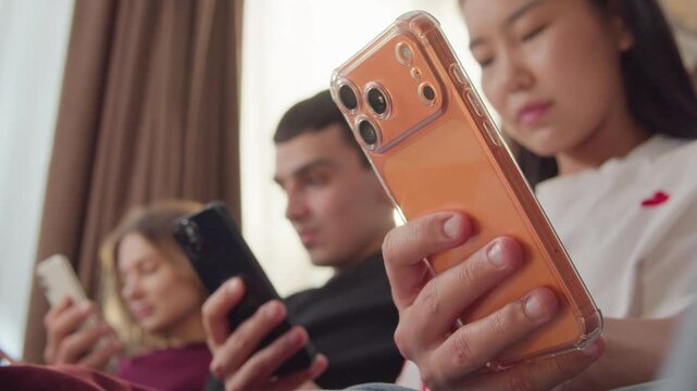 Sad ignore friends sit couch at home living room using smartphone. Addiction social media digital technology, people issue. Cell mobile phone scrolling problem. Useless cellphone internet surfing.