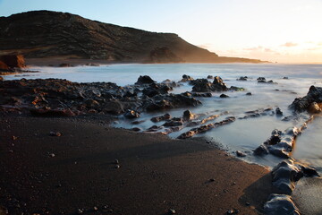 Dramatic sunset at La Cresta del Dragon Colorao, a rocky beach with crashing of waves, located next to Lago Verde (Green lake) in El Golfo, Lanzarote, Canary Islands, Spain