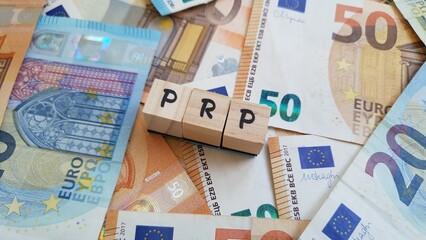 PRP acronym made of wooden letter cubes on pile of Euro banknotes. Plano de Reforma de Pensoo (Pension Reform Plan)