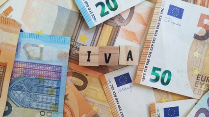 IVA acronym made of wooden letter cubes on pile of Euro banknotes. Imposto sobre o Valor Acrescentado (Value Added Tax)