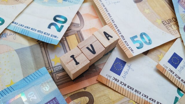 IVA acronym made of wooden letter cubes on pile of Euro banknotes. Imposto sobre o Valor Acrescentado (Value Added Tax)