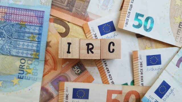IRC acronym made of wooden letter cubes on pile of Euro banknotes. Imposto sobre o Rendimento das Pessoas Coletivas (Corporate Income Tax)