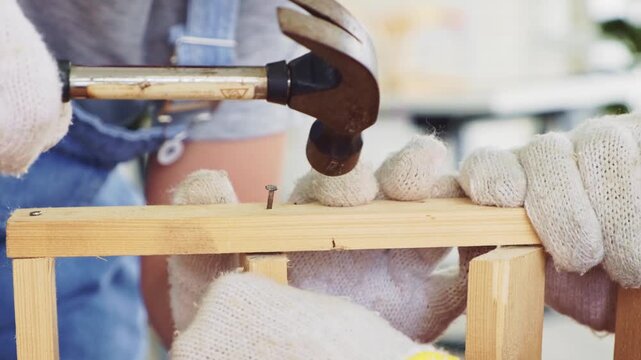 Happy Asian father and son work as a woodworker and carpenter. Father teaching his son to hammer nails on a wooden plank carefully together. carpentry working at a home workshop studio.