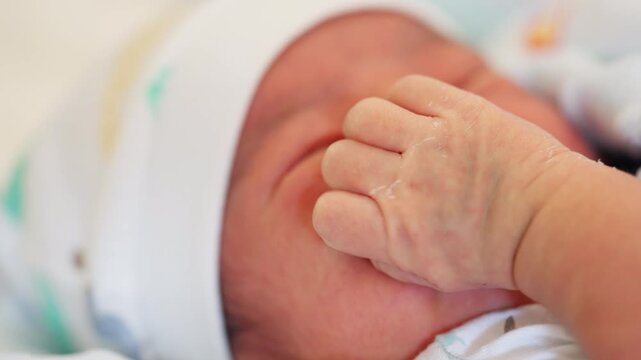 Close-up of a newborn baby crying, wrapped in a blanket. The image captures the raw emotion of infancy and the vulnerability of a newborn needing care and comfort.