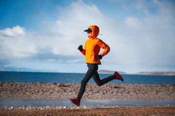 Woman runner running at the winter high altitude lakeside, Tibet