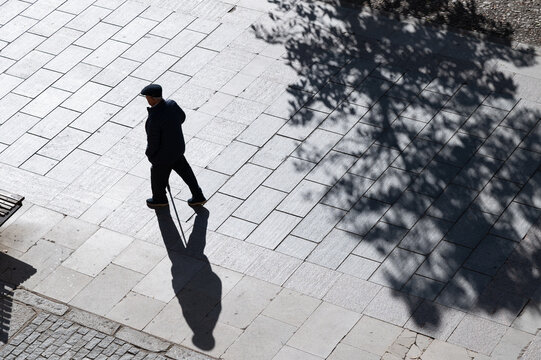 Un anciano con bast&oacute;n pasea por las calles de la ciudad.