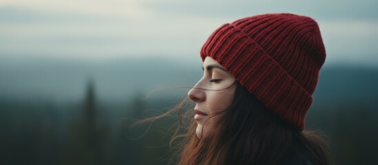 Obraz premium Tranquil Mountain Woman, Peaceful Lady In Scarlet Cap Looks Over Fogcovered Mountains, Relaxed Woman Wearing Crimson Beanie Admires Misty Mountain Landscape In Silence And Serenity