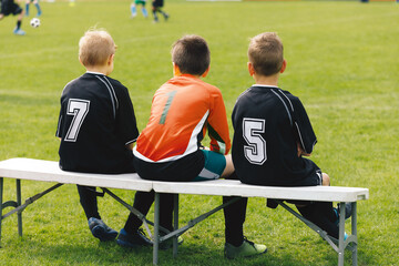 Football soccer match for children. Kids waiting on a bench