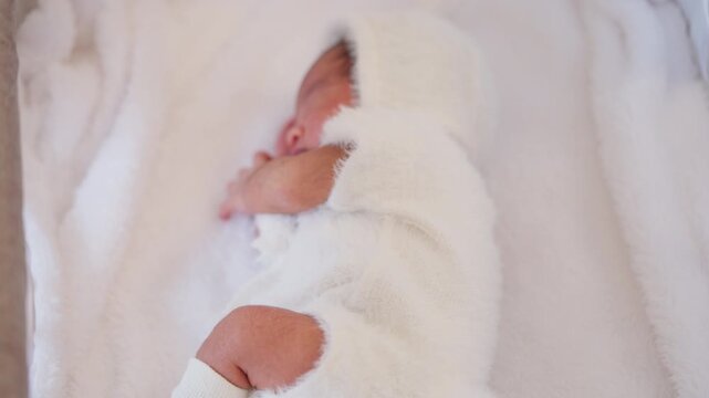 Newborn baby peacefully sleeping on a white soft blanket, dressed in a cozy white fleece outfit. The scene captures purity, warmth, and the fragile beauty of early life.