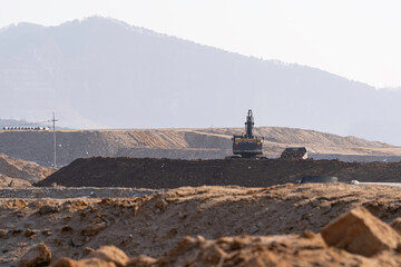 construction site with dirt road and barren land under clear sky, showing early stage infrastructure development and wide open space for future projects.