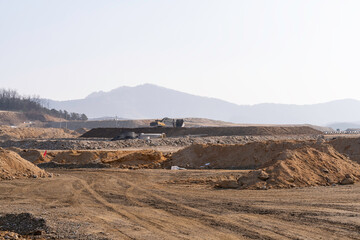 construction site with dirt road and barren land under clear sky, showing early stage infrastructure development and wide open space for future projects.