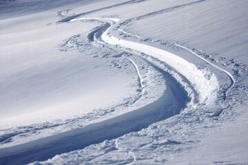 Fresh ski tracks curving across pristine snow slope in winter mountains