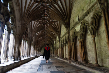 University Student graduating walking canterbury University Student in academic dress walking through an ancient gothic cloister, representing education milestone and historic architecture. Canterbury
