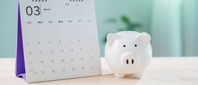 Money save plan using saving calendar, piggy bank, financial, manage retirement insurance, date tax growth, organize and prepare monthly budget on wooden office table surface