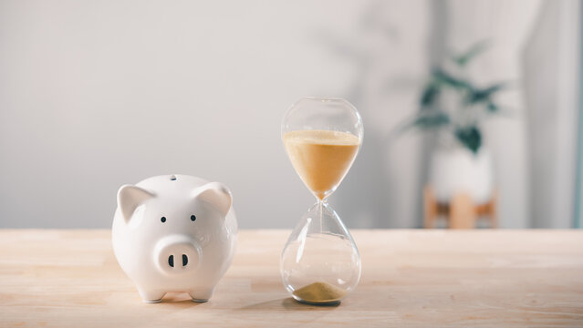 Hourglass with piggy bank and saving money to reduce company cost, business budget and time management for productivity while financial saving helps save bank account balance