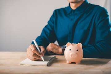 Piggy bank learning education saving college career growth plans help man in blue shirt writing budget in notebook for university tuition fees and professional academic development