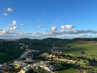 Small rural village in green valley with winding road, hills and dramatic clouds, peaceful countryside life