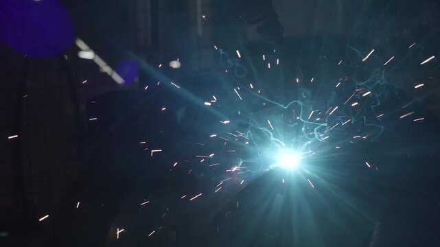 Robotic arm welding metal creating sparks and smoke