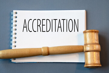 ACCREDITATION - word in a white notebook on a gray background with a judge's gavel