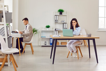 Obraz premium Business people at work in modern office space, man and woman colleagues coworking at own desk place. Businessman, businesswoman share comfortable office lounge room in corporate workplace environment