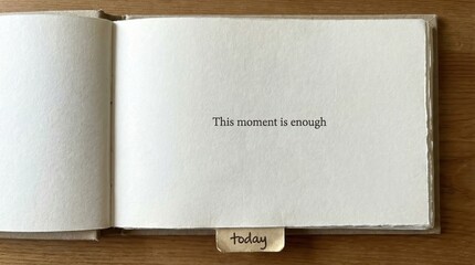 Inspirational quote 'This moment is enough today' in an open book