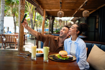 Young couple sharing dining experience at tropical restaurant, engaging with their online followers