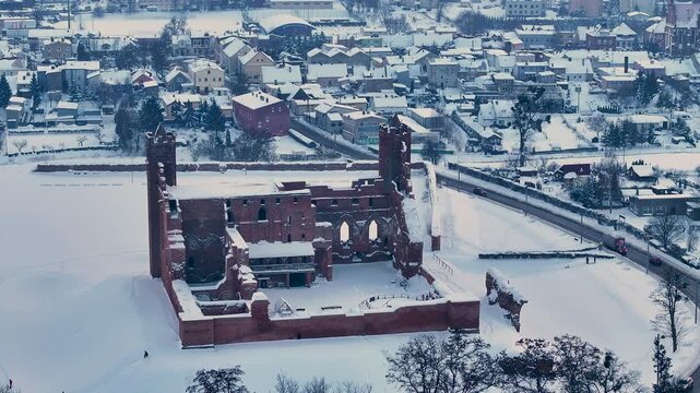 Aerial winter Teutonic Castle overhead Radzyn Poland 4K. Brick Gothic monastery castle built 1234 AD Teutonic Knights 10th century. Historical buildings, tourist attractions, parks, farms.