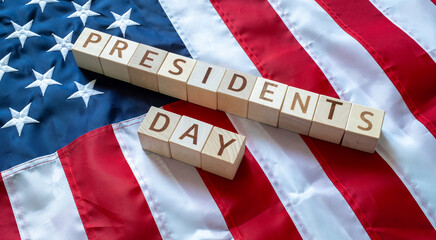 PRESIDENT'S DAY word made by wooden blocks over United States of America flag