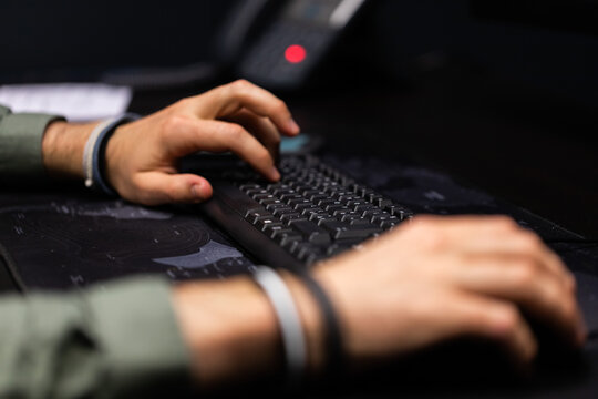 mani di giovane uomo adulto caucasico che scrive su una tastiera per computer, seduto ad un tavolo, in un ufficio