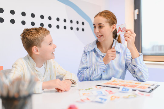 Teacher tutoring young boy learning alphabet letters