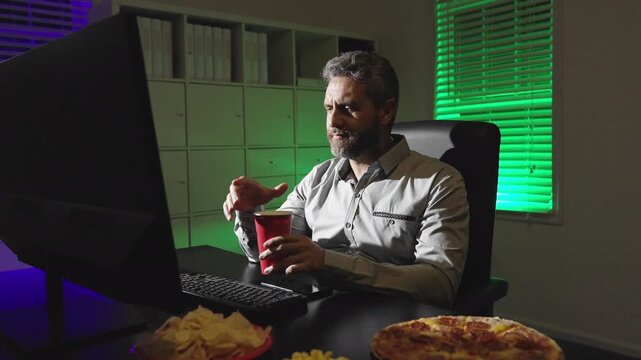 Late night work with laptop and snacks. Late night work with junk food habit. Late night work at desk eating chips. Office night mood with computer light.