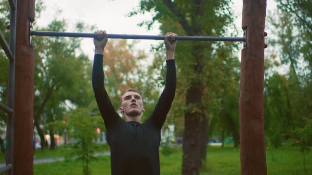young athlete performing pullups outdoors, training on wooden bar in leafy park, focused grip and steady breathing, progression from hang to chin above bar, scene evokes determination and calm