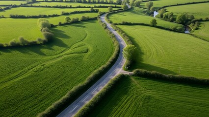 Fototapeta premium Aerial view of rural countryside road through green farmland landscape
