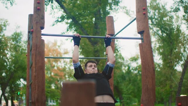 Caucasian man completing pullup with effort, chin clearing bar, shoulders fully engaged, determined face, late afternoon light filtering through leaves, sense of accomplishment and strength at outdoor