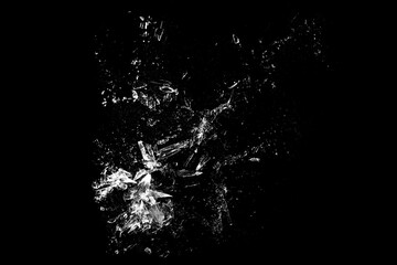 Broken glass fragments scattered with dust particles on black background