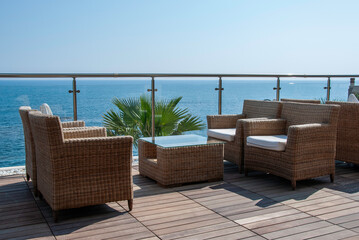 Naklejka premium Oceanfront Balcony With Wicker Seating, Glass Table, and Calm Sea View for Relaxation and Luxury Outdoor Living