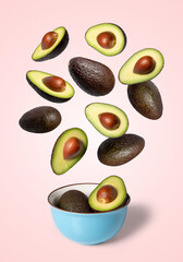 Avocados falling into bowl on pink background