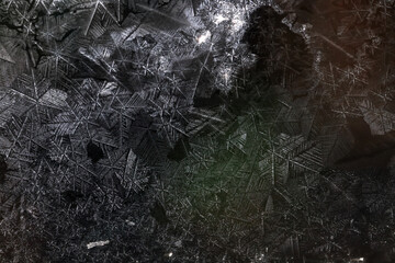 Ice crystals freezing on a black background, abstract winter photo surface © kichigin19