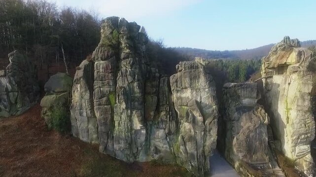 Drone orbiting around Externsteine sandstone rock formations surrounded by forest