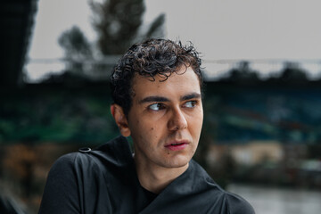 Fototapeta premium Young caucasian male with curly hair outdoors looking thoughtful